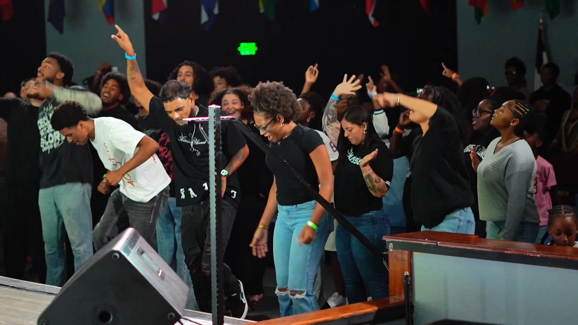 Young people at a Solid Rock youth night, hands raised in a darkened room lit in blue and magenta